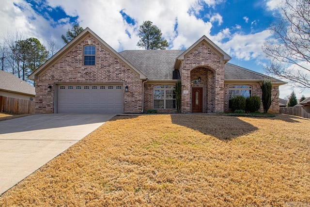 traditional home featuring a front yard, fence, a shingled roof, concrete driveway, and brick siding