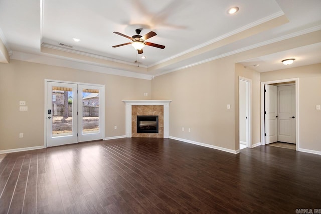 unfurnished living room with dark wood-style floors, baseboards, a fireplace, ornamental molding, and a raised ceiling