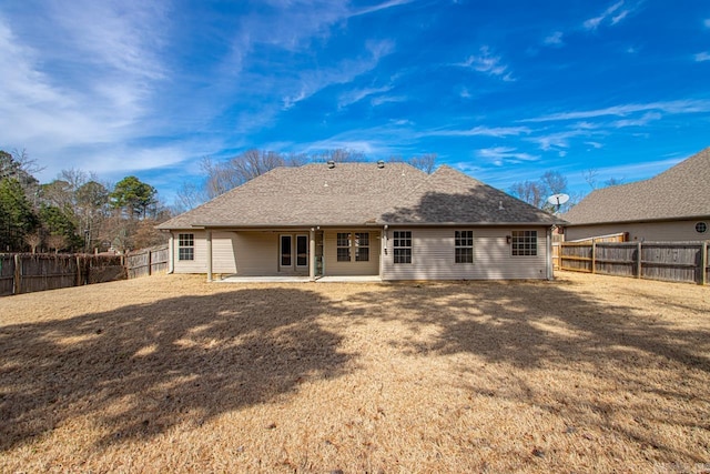 back of house with a yard, a shingled roof, a fenced backyard, and a patio area