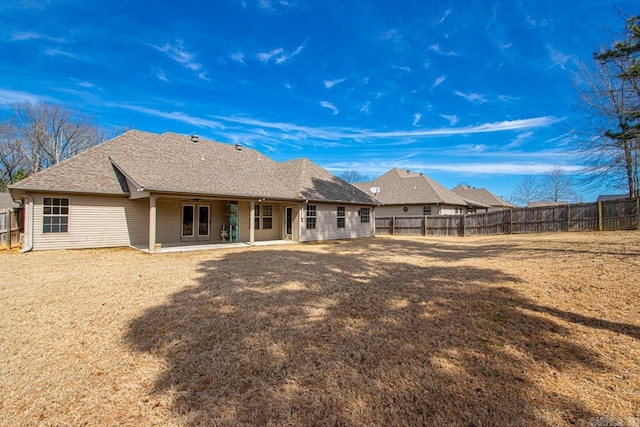 rear view of house featuring a shingled roof, a fenced backyard, and a patio area