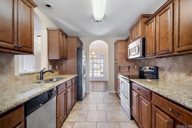 kitchen featuring visible vents, a sink, stainless steel appliances, arched walkways, and decorative backsplash