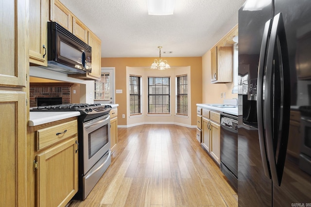 kitchen with light brown cabinets, light wood-style flooring, black appliances, light countertops, and a textured ceiling