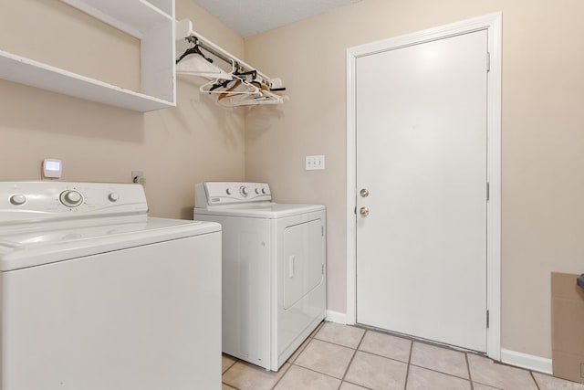 washroom with washing machine and clothes dryer, laundry area, baseboards, and light tile patterned floors