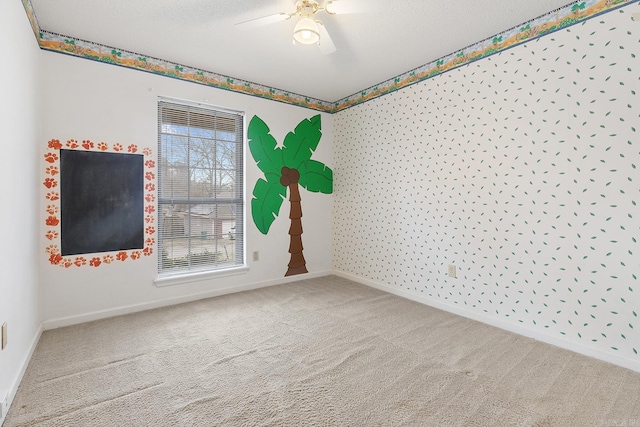 carpeted empty room with baseboards, a textured ceiling, and a ceiling fan