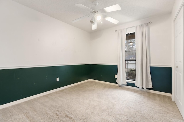 carpeted spare room featuring a ceiling fan, baseboards, and a textured ceiling