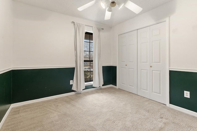 unfurnished bedroom with carpet flooring, baseboards, a closet, and ceiling fan