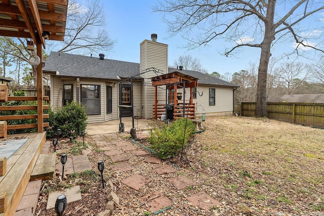 rear view of property with a chimney, fence private yard, a patio, and a shingled roof