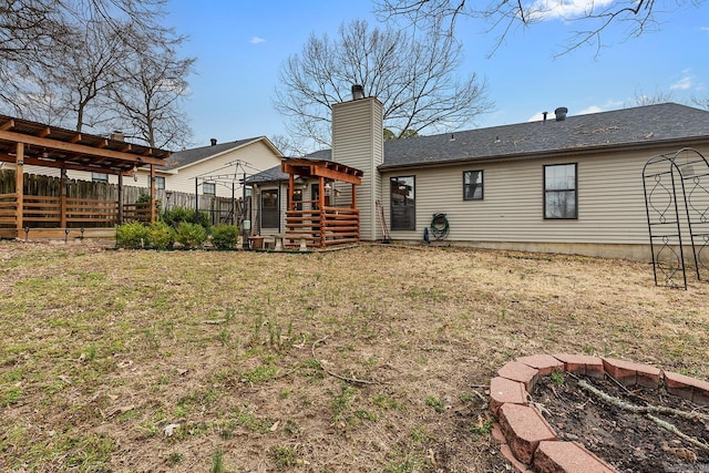 rear view of house featuring a yard, fence, and a chimney