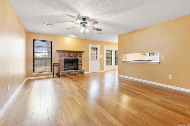 unfurnished living room with a wealth of natural light, visible vents, a fireplace, and light wood-type flooring