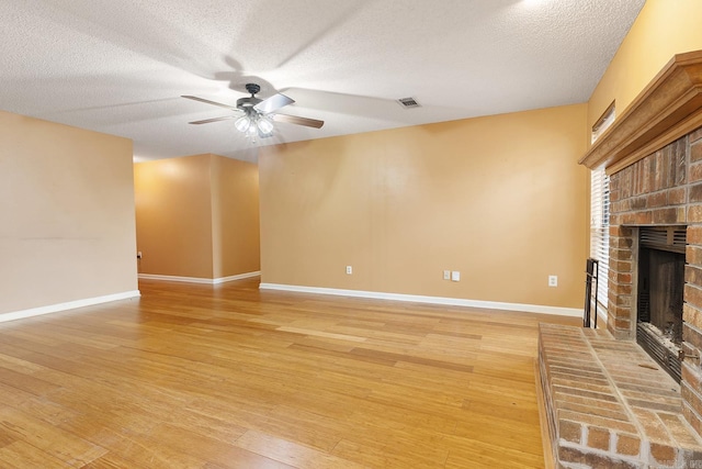 unfurnished living room with visible vents, light wood-style flooring, a fireplace, and ceiling fan