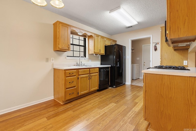 kitchen with black appliances, light wood-style floors, light countertops, and a textured ceiling