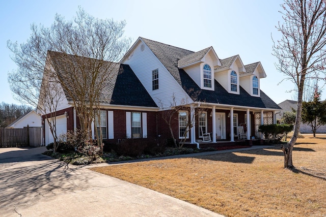 cape cod house featuring fence, covered porch, a front yard, a garage, and brick siding