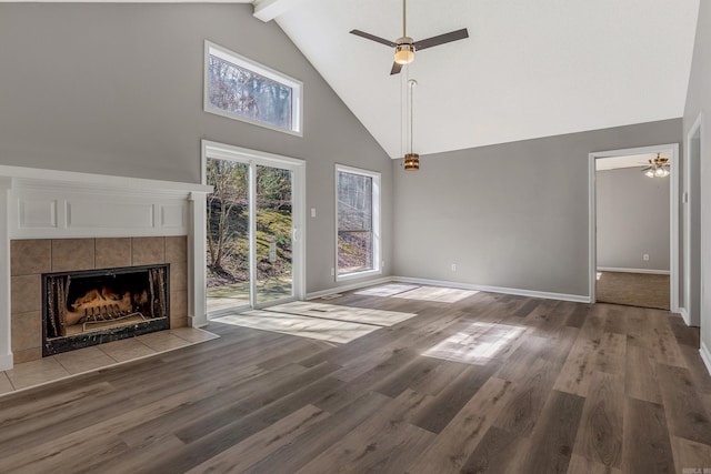 unfurnished living room featuring a tiled fireplace, wood finished floors, and a ceiling fan