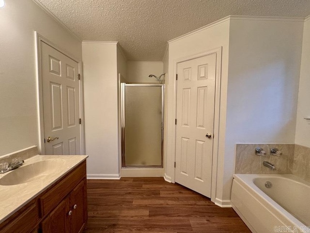 bathroom featuring crown molding, a garden tub, a stall shower, wood finished floors, and a textured ceiling