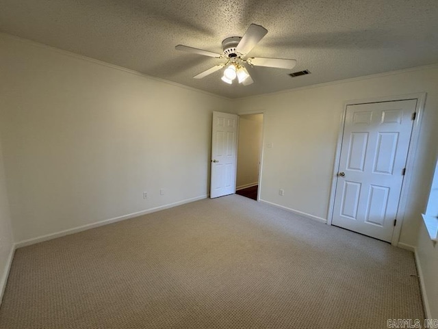 unfurnished bedroom featuring ornamental molding, visible vents, carpet floors, and a textured ceiling