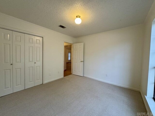 unfurnished bedroom featuring carpet, baseboards, visible vents, a closet, and a textured ceiling