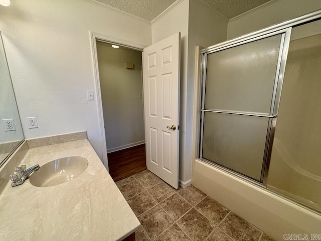 bathroom featuring vanity, baseboards, enclosed tub / shower combo, ornamental molding, and a textured ceiling