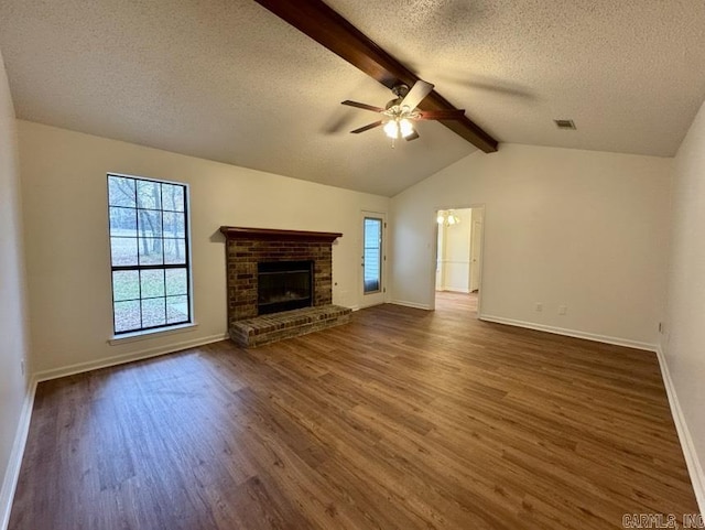 unfurnished living room with a fireplace, lofted ceiling with beams, wood finished floors, and ceiling fan