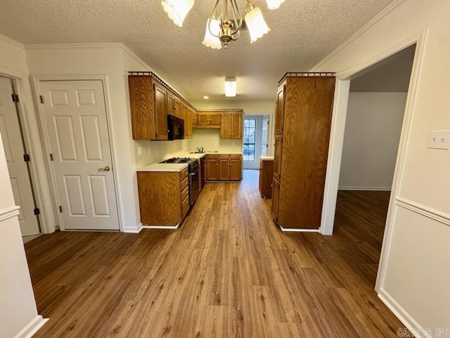 kitchen with brown cabinets, black appliances, light countertops, and wood finished floors