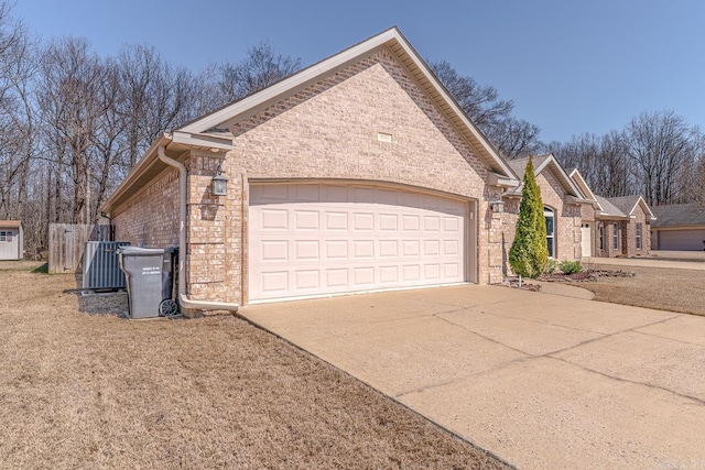 view of side of property with a garage, brick siding, central AC, and driveway