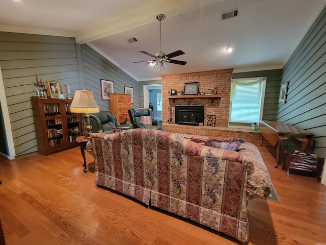 living room featuring vaulted ceiling with beams, wood finished floors, visible vents, and ceiling fan