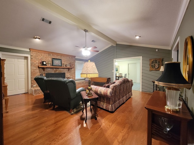 living room with visible vents, a brick fireplace, ceiling fan, lofted ceiling with beams, and light wood-style floors