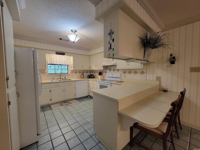 kitchen featuring ornamental molding, a sink, white appliances, a peninsula, and light countertops