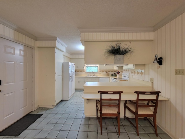 kitchen with ornamental molding, a sink, white fridge with ice dispenser, a peninsula, and stove