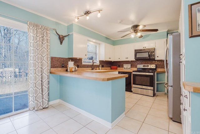 kitchen featuring appliances with stainless steel finishes, light countertops, a peninsula, and a sink