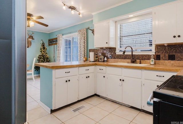 kitchen with decorative backsplash, crown molding, visible vents, and a sink