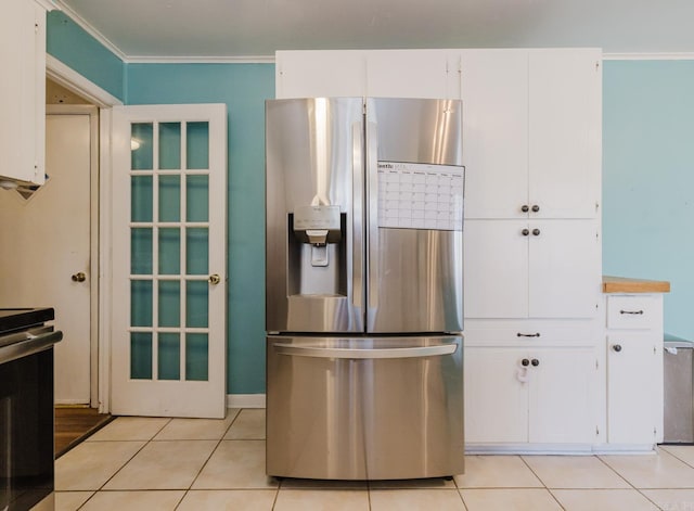 kitchen with light tile patterned floors, stainless steel fridge with ice dispenser, ornamental molding, stove, and white cabinetry