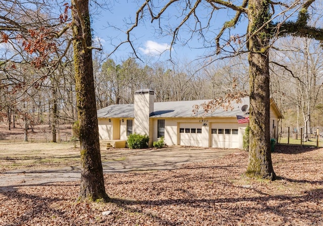 view of front facade featuring a garage, a chimney, and driveway