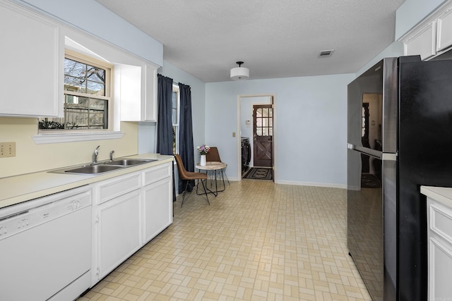 kitchen with visible vents, a sink, freestanding refrigerator, white cabinets, and dishwasher
