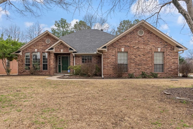 view of front facade featuring a front lawn, brick siding, and roof with shingles