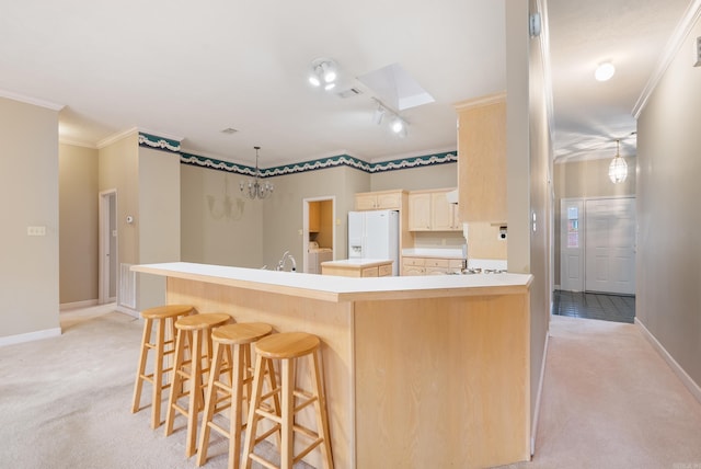 kitchen featuring washer / dryer, light colored carpet, white fridge with ice dispenser, and ornamental molding