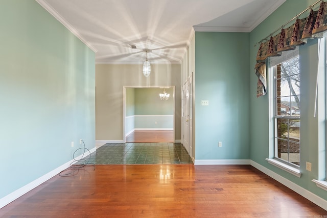 unfurnished room featuring baseboards, a notable chandelier, wood finished floors, and ornamental molding