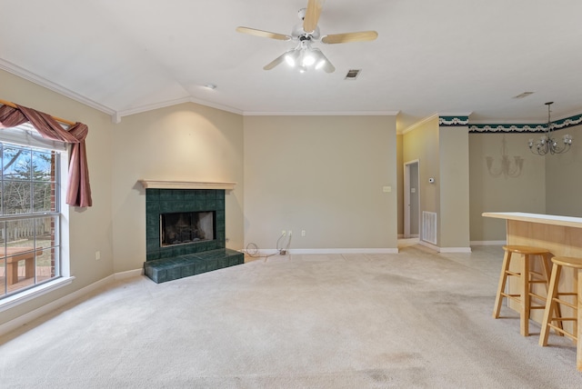 living room featuring a tiled fireplace, crown molding, baseboards, light colored carpet, and vaulted ceiling