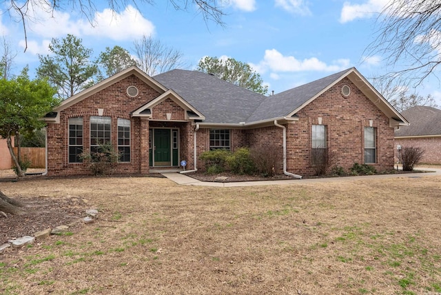 view of front of home featuring brick siding, a front lawn, and a shingled roof