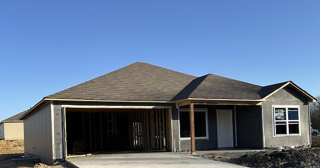 property in mid-construction with roof with shingles, concrete driveway, and an attached garage