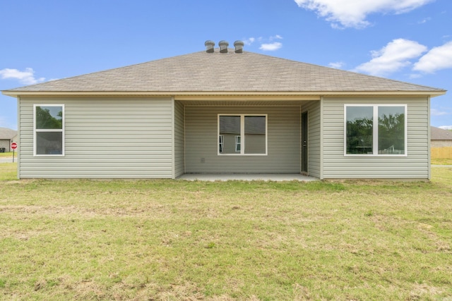 rear view of property featuring a patio, a yard, and roof with shingles