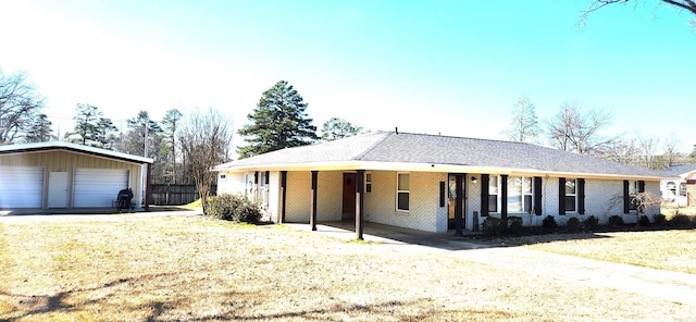 ranch-style home with a garage, brick siding, an outdoor structure, and a front lawn