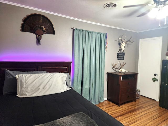 bedroom with visible vents, ornamental molding, ceiling fan, and wood finished floors