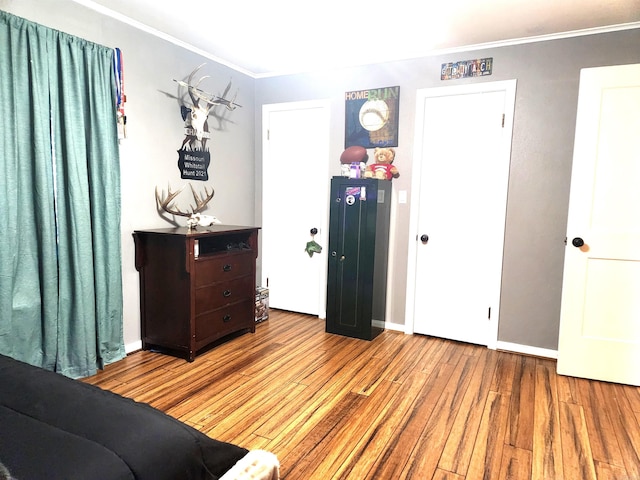 bedroom with crown molding, wood finished floors, and baseboards