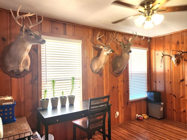 interior space featuring wood walls, ceiling fan, and wood finished floors