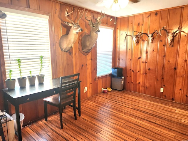 home office featuring hardwood / wood-style flooring, wooden walls, a wealth of natural light, and ceiling fan