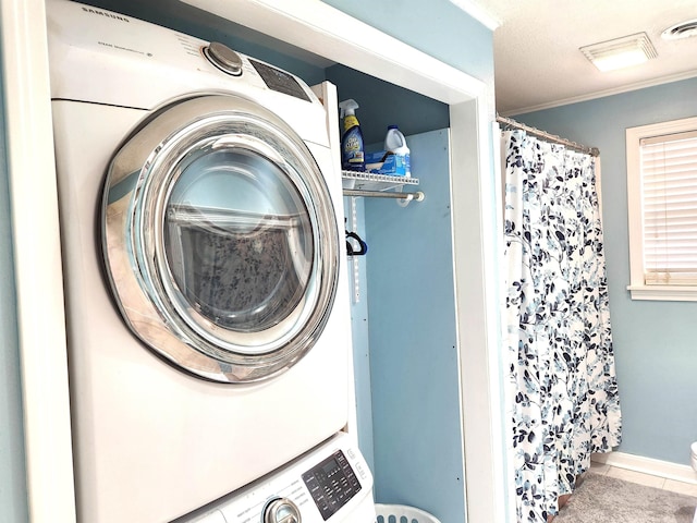 washroom featuring tile patterned floors, ornamental molding, visible vents, and stacked washing maching and dryer