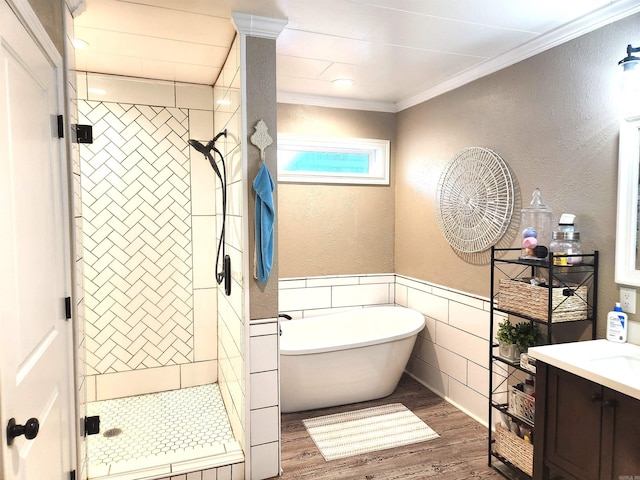 full bath featuring a stall shower, wood finished floors, wainscoting, crown molding, and a soaking tub