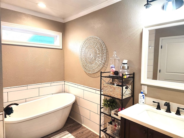 bathroom featuring crown molding, a wainscoted wall, a freestanding tub, wood finished floors, and vanity