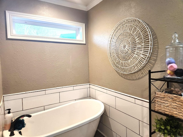 bathroom with crown molding, a textured wall, a wainscoted wall, and a freestanding bath