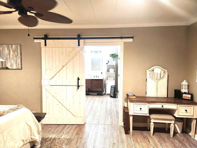 bedroom featuring a barn door, wood finished floors, and ornamental molding